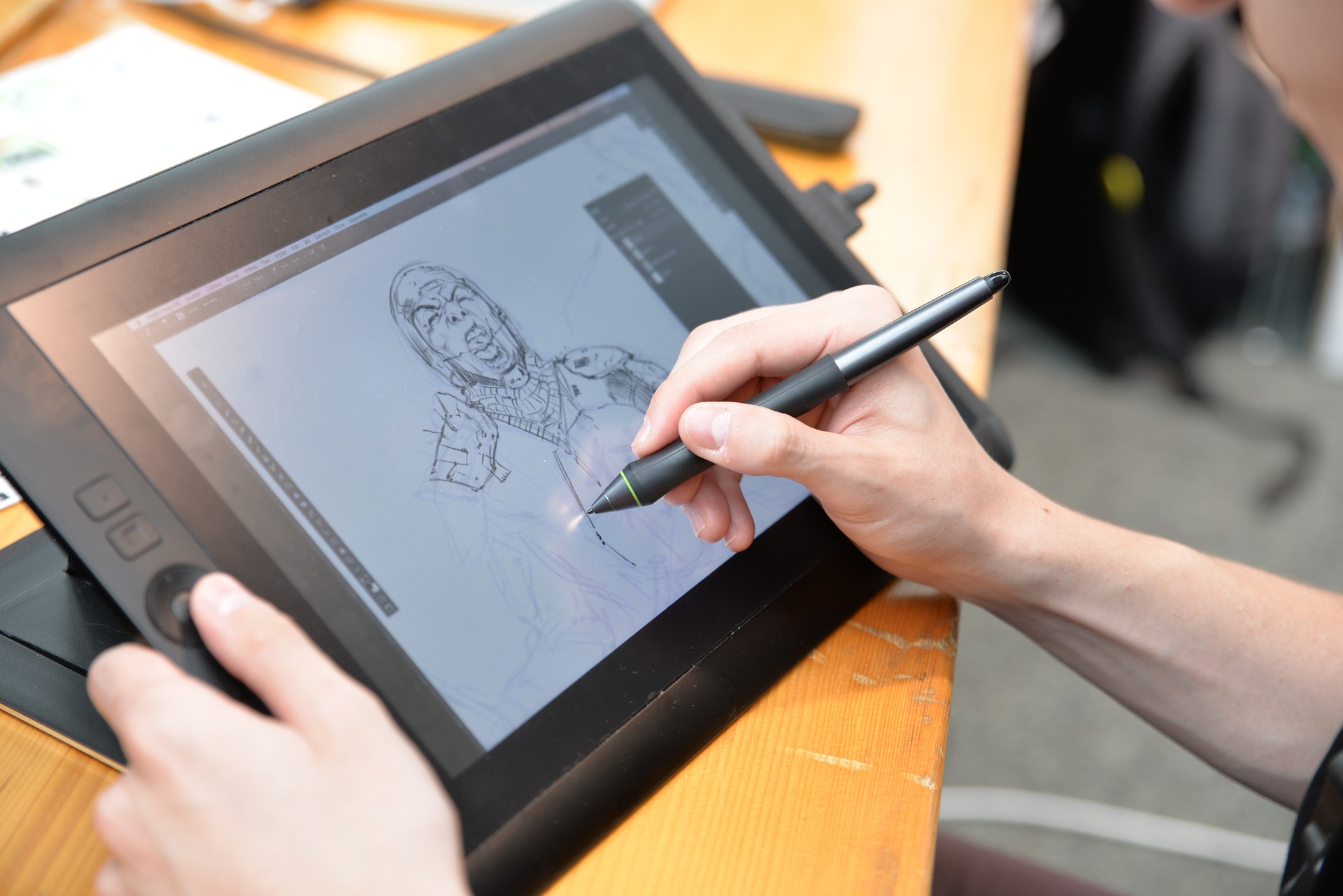 Homem desenha em tablet um personagem utilizando uma caneta específica para o equipamento.