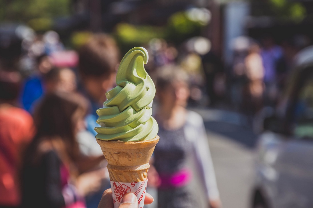A imagem mostra uma pessoa segurando um cone de sorvete da cor verde. O sabor é de abacate.