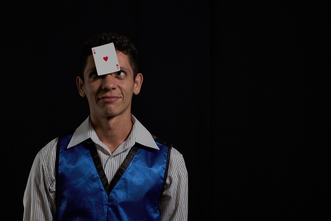 mágico à esquerda da foto com uma carta de baralho no rosto