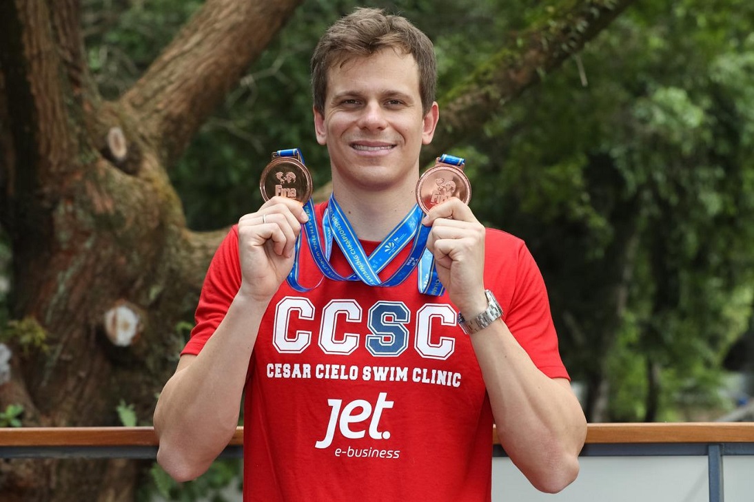 campeão olímpico César Cielo segurando duas medalhas, uma em cada mão