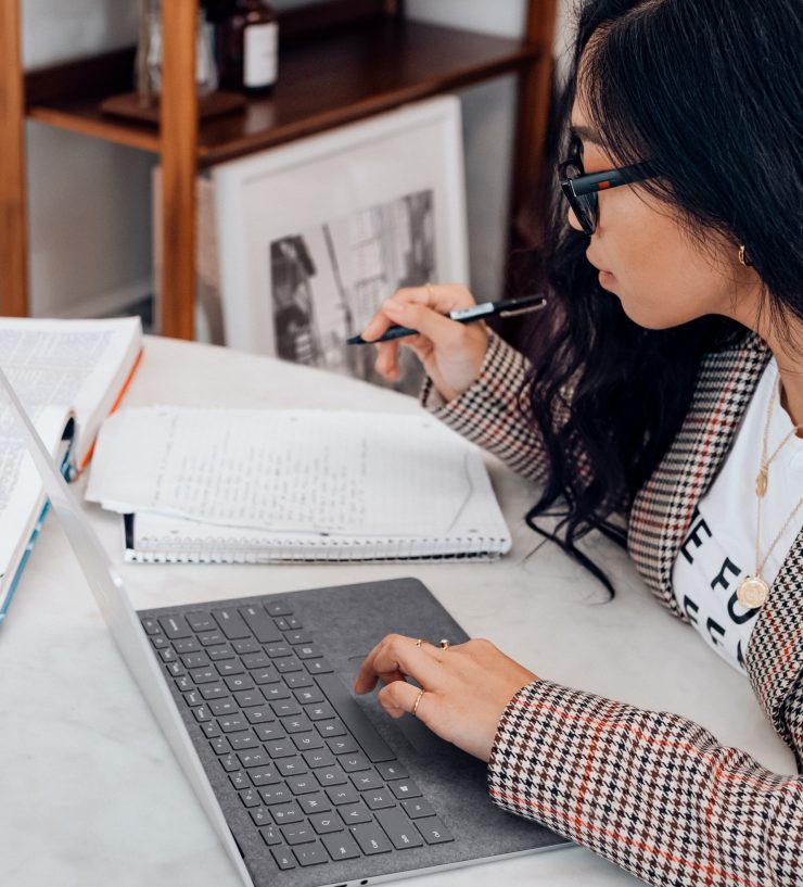 Mulher com notebook, caneta e caderno, em posição de estudar online