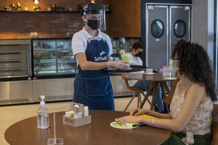 Homem serve uma cliente, utilizando máscara de proteção; cursos gratuitos na área de varejo e restaurantes são ofertados 