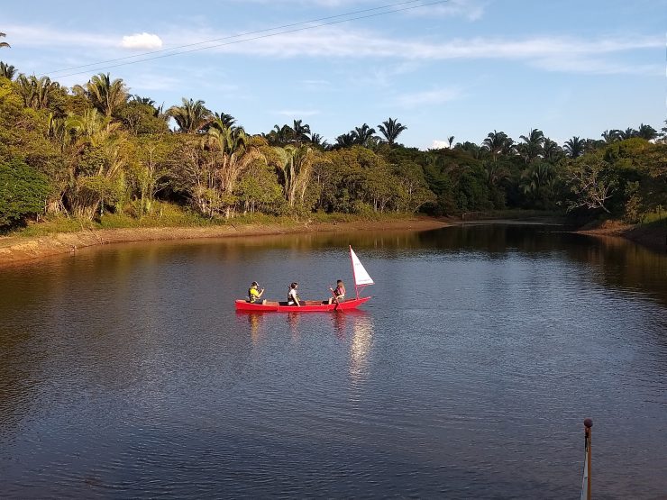 Lagoa de Guaraciaba do Norte, com barco vermelho e três pessoas a bordo; passeio virtual é ofertado