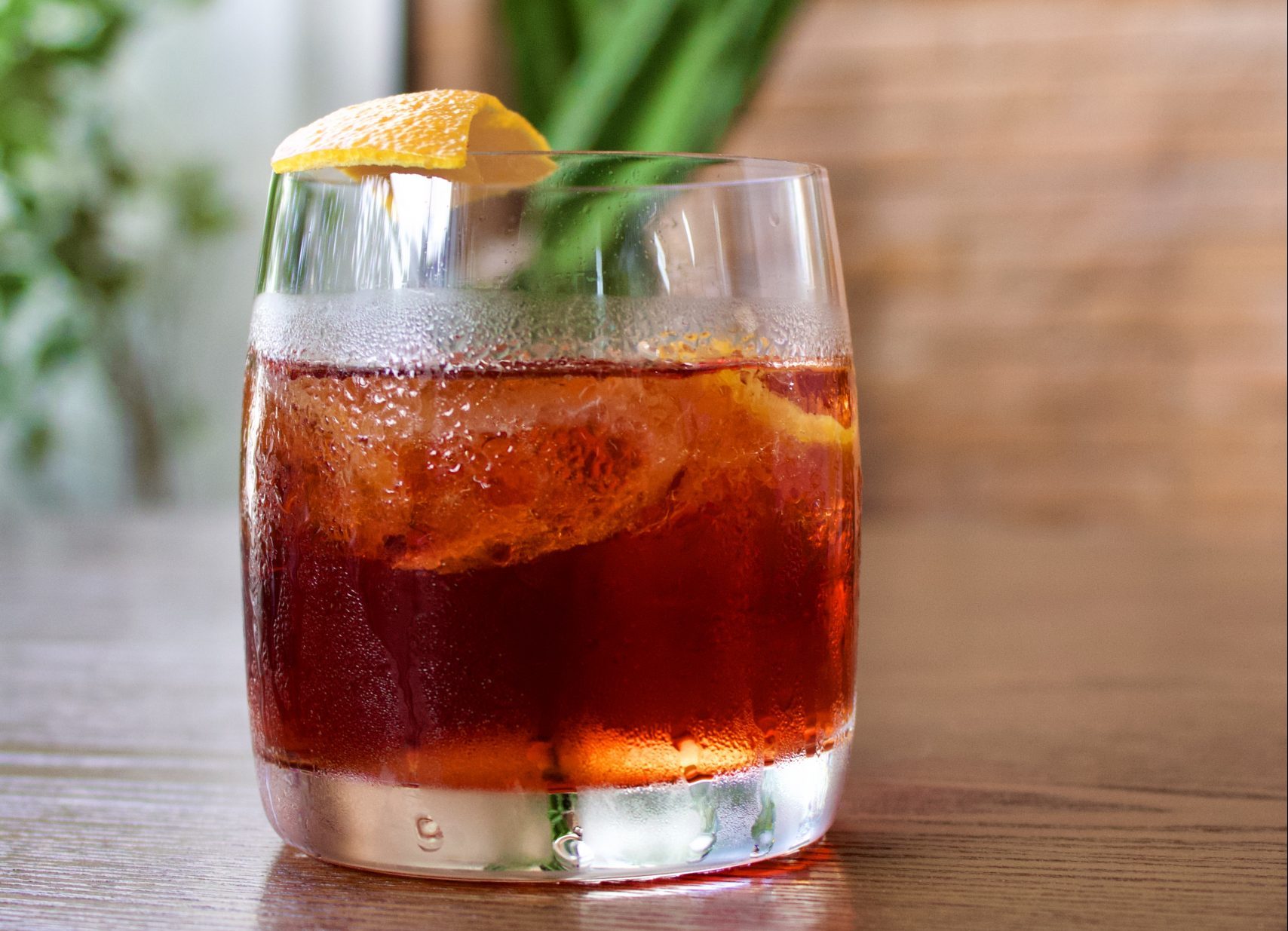Drinque de Negroni: copo de vidro com líquido laranja, gelo e casca de laranja na borda