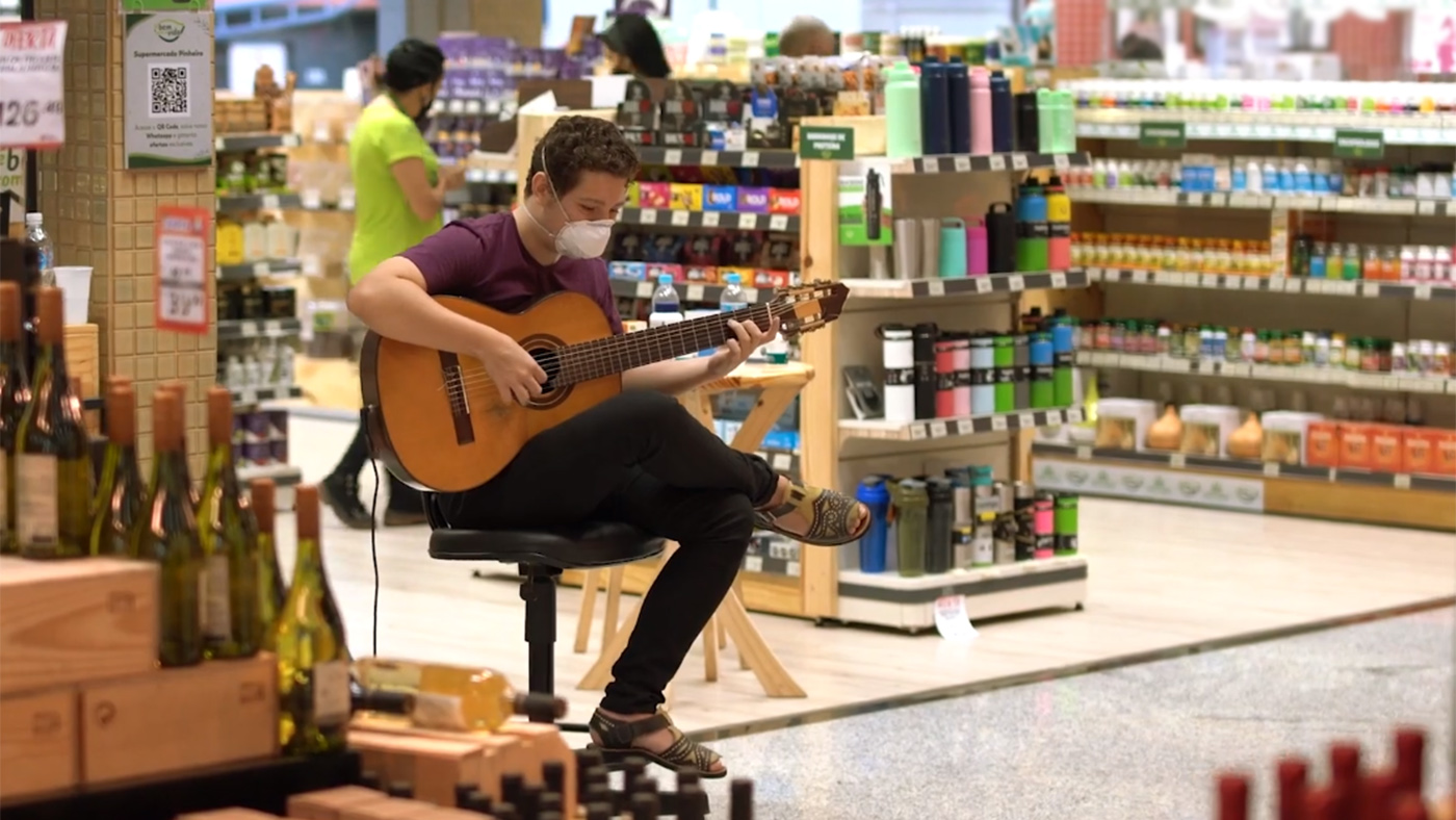artistas: homem tocando violão em meio a supermercado