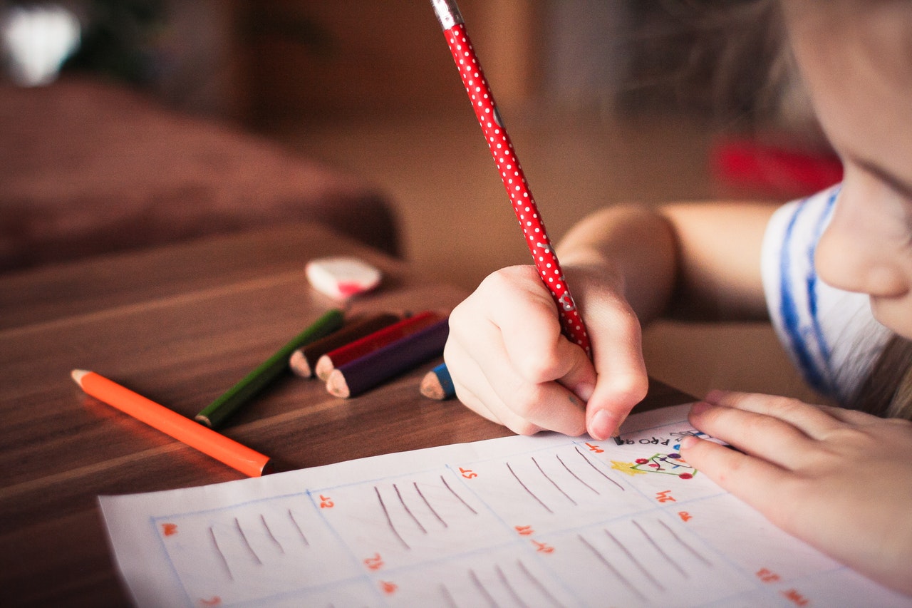 Escola: criança escrevendo em caderno com lapis