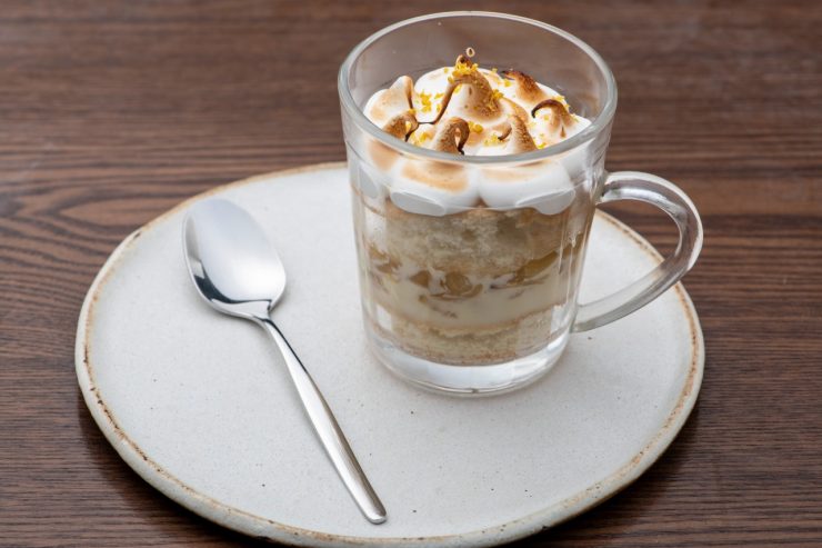 Café Senac: uma xícara transparente com um café cremoso em um prato branco, ao lado de uma colher
