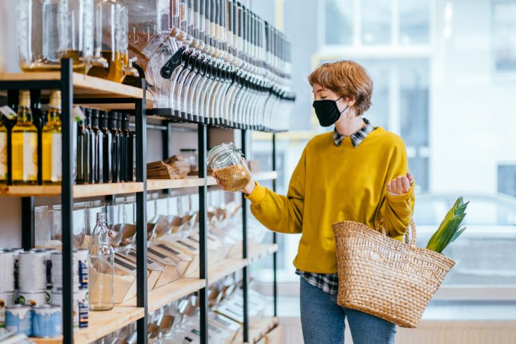socioambiental: mulher de mascára escolhendo produtos em uma prateleira
