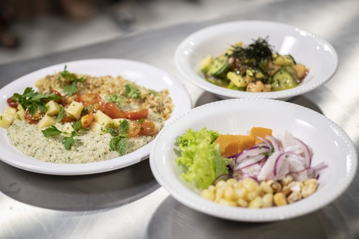 Lei da Gastronomia: na imagem, há três pratos de comida em cima de uma mesa de metal. Os pratos são brancos e as refeições, bem coloridas, com muitos vegetais e grãos.