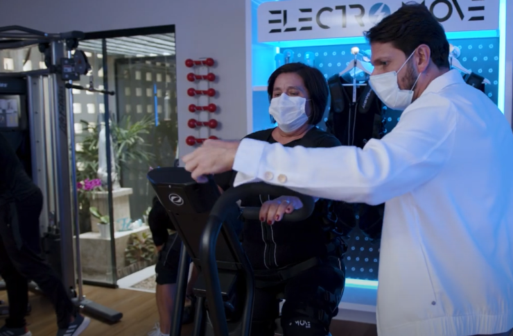 Tecnologia e saúde: o fisioterapeuta José Meudo acompanha uma paciente na clínica. Ambos usam máscaras.