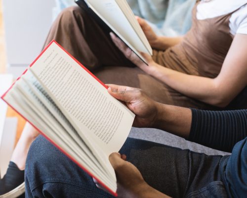 Escola Senac do Livro: a foto mostra braços de duas pessoas, uma branca e uma negra, segurando livros abertos