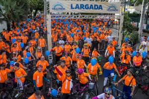 CicloSesc: imagem de uma faixa de largada com vários ciclistas com camisas laranjas e capacetes embaixo